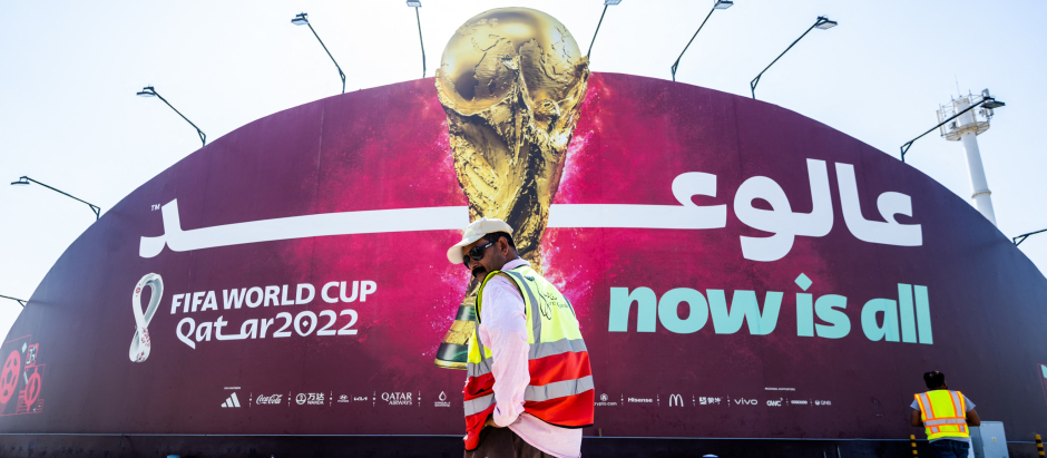 Un trabajador en Qatar, frente a uno de los grandes carteles que anuncian el Mundial