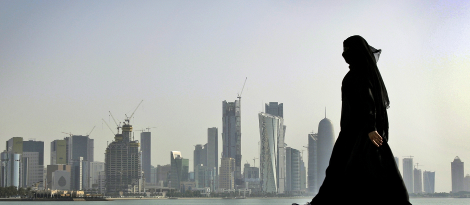 FILE- In this May 14, 2010 file photo, a Qatari woman walks in front of the city skyline in Doha, Qatar. A worker on a Qatar World Cup stadium site has died in the first work-related fatality to be announced by organizers of the 2022 soccer tournament which has been dogged by concerns about labor conditions. Qatar has previously reported three deaths at stadium construction sites but said they were not ‚Äúwork-related.‚Äù  (AP Photo/Kamran Jebreili, File)