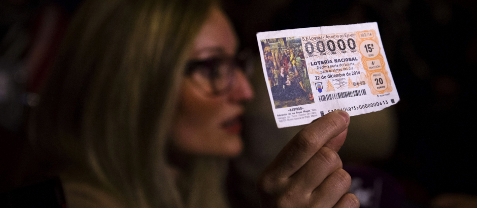 Una mujer muestra su décimo premiado con el número 00000 en 2014