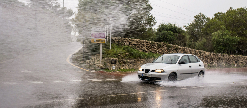 Un vehículo circula bajo la lluvia por una carretera en Sant Lluís (Menorca)