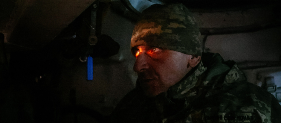 This photograph taken on November 30, 2022 shows a Ukrainian artilleryman looking through a periscope of a 2S3 Akatsiya (Self propelled howitzer) towards Russian positions in a field near an undisclosed frontline position in eastern Ukraine, amid the Russian invasion of Ukraine. (Photo by Yevhen TITOV / AFP)