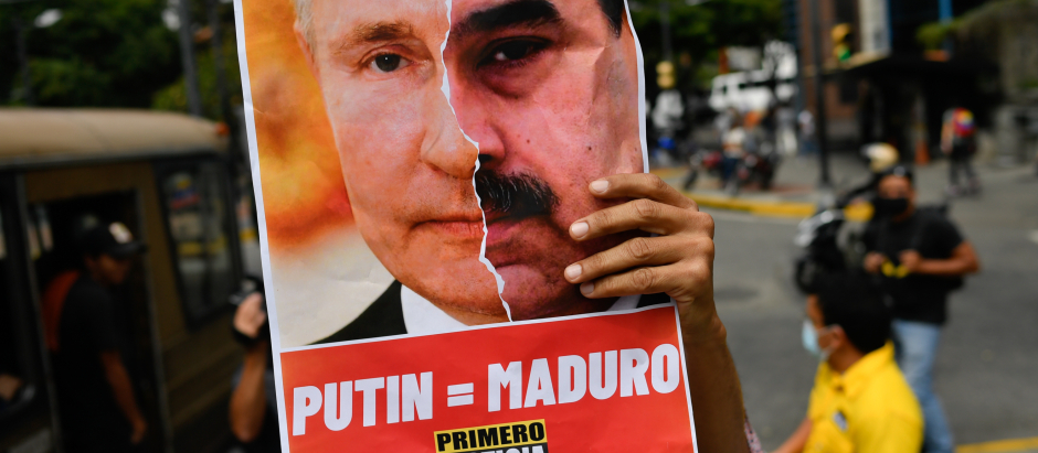 Un miembro del partido opositor Primero Justicia sostiene una pancarta que muestra el rostro del presidente ruso, Vladimir Putin, y el presidente venezolano, Nicolás Maduro