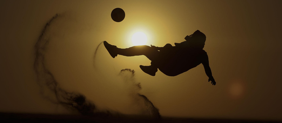 Un turista juega al fútbol mientras disfruta de un paseo en el desierto de Qatar, país que celebra estos días el Mundial de fútbol Qatar 2022