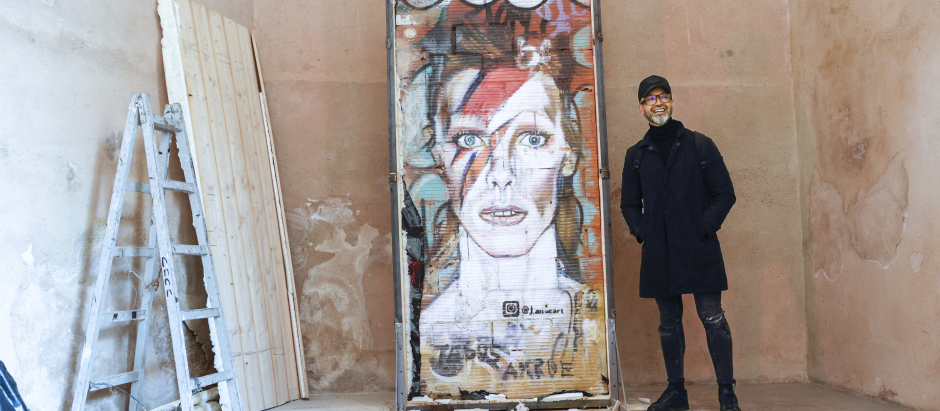 El artista Jesús Arrúe posa con el el grafiti de David Bowie que dibujó en un muro de la ciudad de Valencia que ahora se encuentra en el museo del Carm