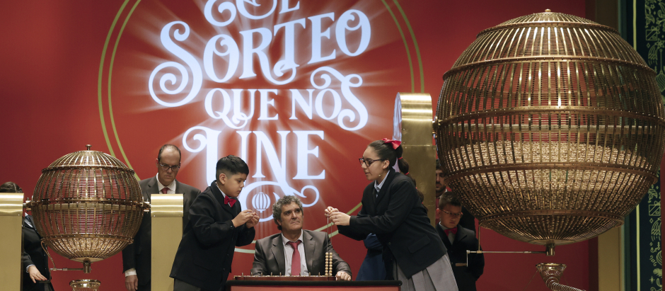 Luis Alcides Paniagua (i) canta los números mientras su compañera Kiara Román Benitez (d) canta premios durante el sorteo de El Gordo de Navidad en el Teatro Real en Madrid, este jueves. EFE/ Javier Lizón