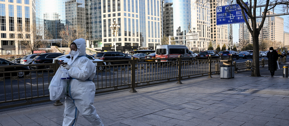 Una mujer caminando por Pekín con un EPI para evitar contagiarse de la covid