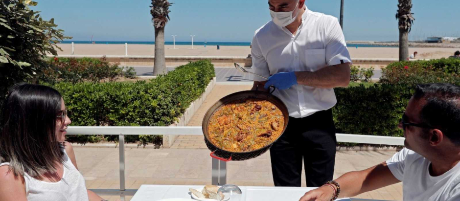 Un camarero enseña una paella en la valenciana playa de La Malvarrosa