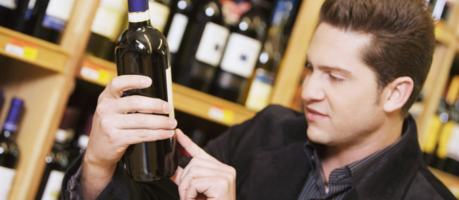Un hombre lee la etiqueta de un vino en un supermercado