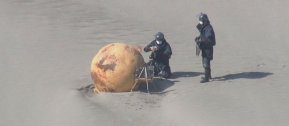Dos especialistas analizan la bola metálica aparecida en una playa japonesa