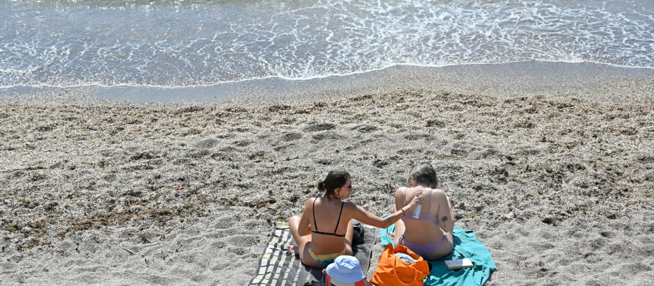 Unas chicas toman el sol en bañador junto al mar aprovechando las altas temperaturas, a 11 de marzo de 2023