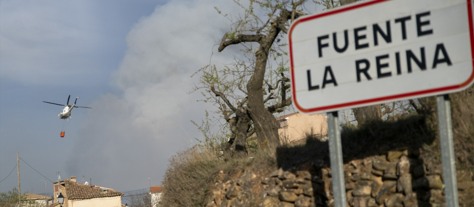 Vista de un helicóptero y una columna de humo provocada por un incendio forestal originado en Villanueva de Viver, a la entrada del municipio de Fuente de la Reina