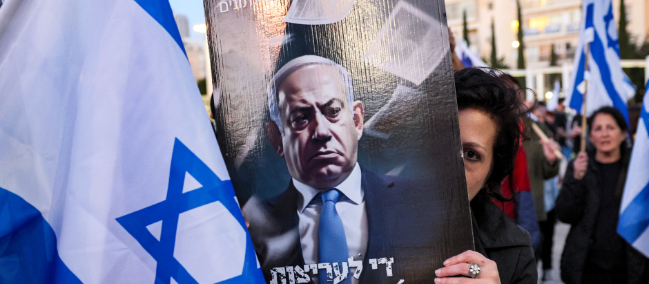 Una manifestante se cubre la cara con un cartel contra el primer ministro israelí Benjamin Netanyahu