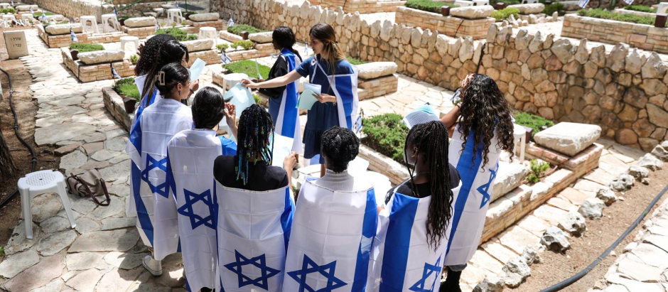 Adolescentes envueltos en banderas israelíes visitan las tumbas de los soldados israelíes caídos en el cementerio militar del Monte Herzl