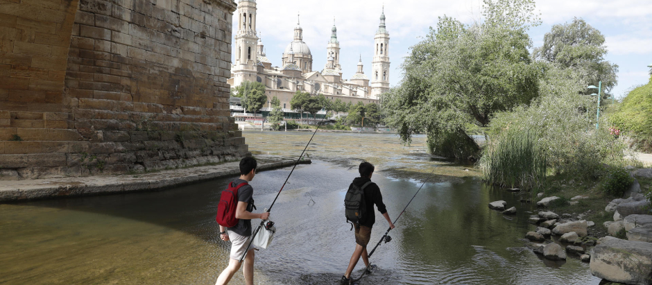 Dos personas caminan por el cauce del río Ebro a su paso por Zaragoza
