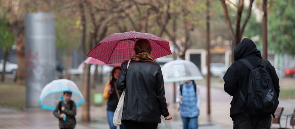 Varias personas con paraguas pasean por una calle de Barcelona