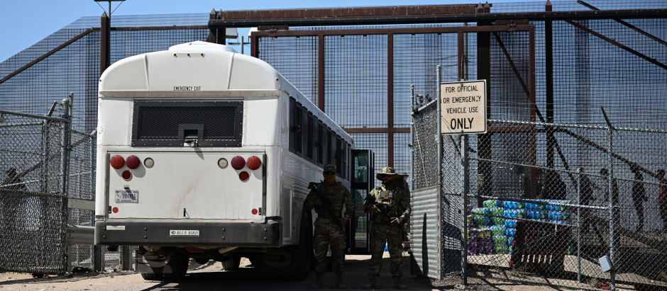 La Guardia Nacional del Ejército de Texas observa cómo los migrantes suben a un autobús tras entregarse a la Oficina de Aduanas y Protección de Fronteras (CBP) de EE.UU.
