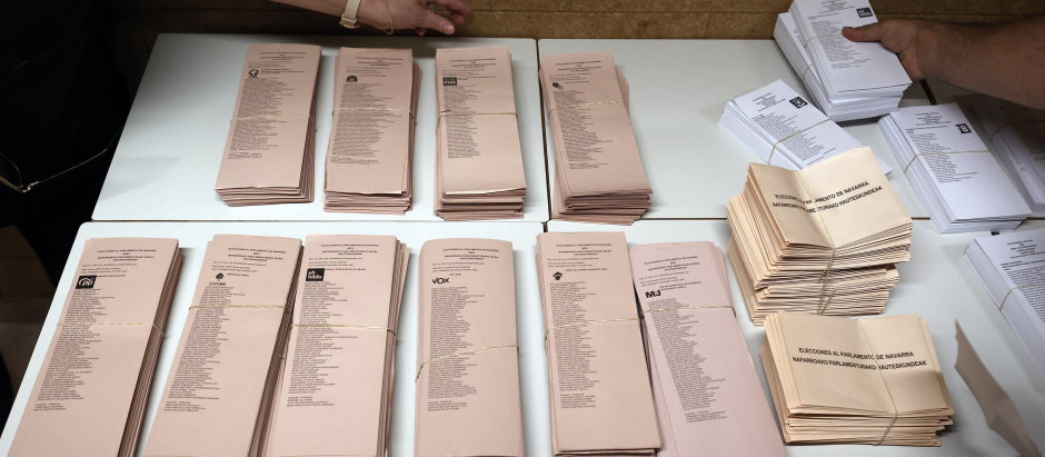 Varios responsables de mesa colocan las papeletas electorales sobre una mesa
