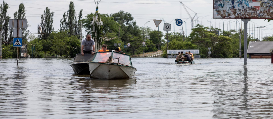 Residentes y trabajadores de los servicios de rescate usan barcas para moverse en una zona inundada de Jersón, Ucrania