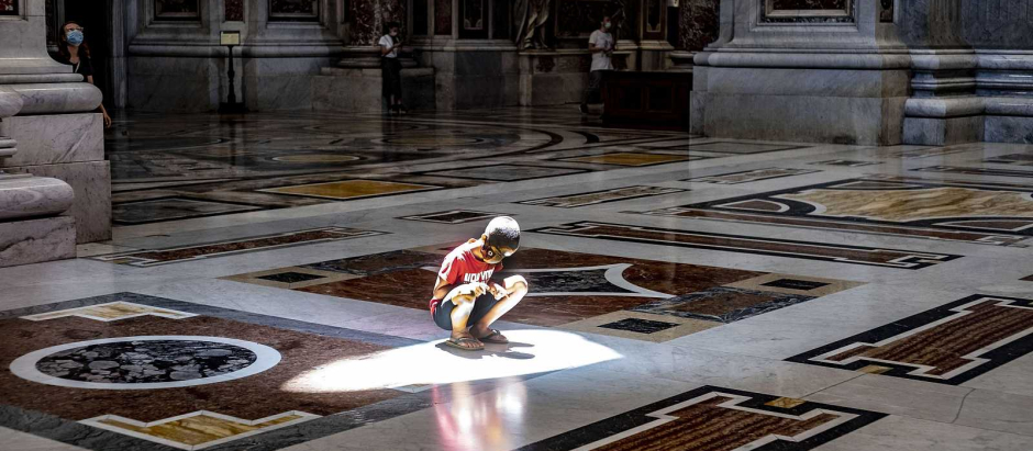 Un niño juega con su sombra en el suelo de la Basílica de San Pedro del Vaticano