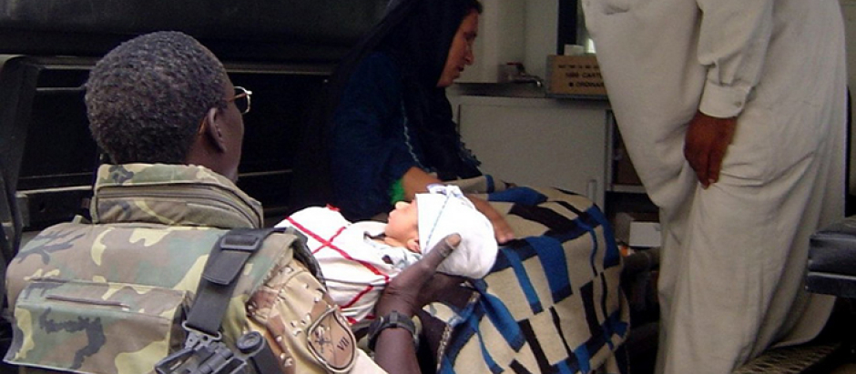 Legionario de la VII Bandera, armado con un fusil HKG36, atendiendo a un bebé árabe.