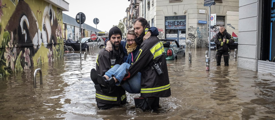 Los trabajadores de emergencia llevan a una mujer en medio de inundaciones en una calle, después de que una tormenta causó el desbordamiento del río Seveso