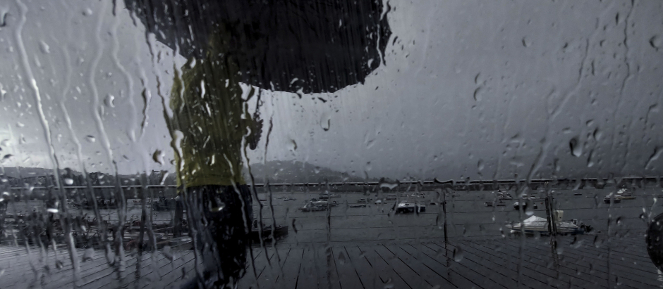Un hombre con paraguas caminaba este lunes por el puerto de Pontedeume, en una jornada marcada nuevamente por las lluvias