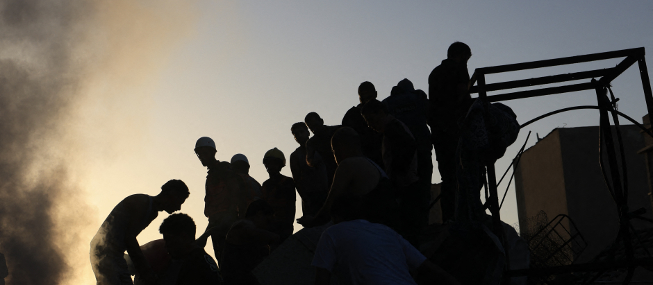 Los palestinos buscan entre los escombros de un edificio derrumbado supervivientes y víctimas tras el bombardeo israelí