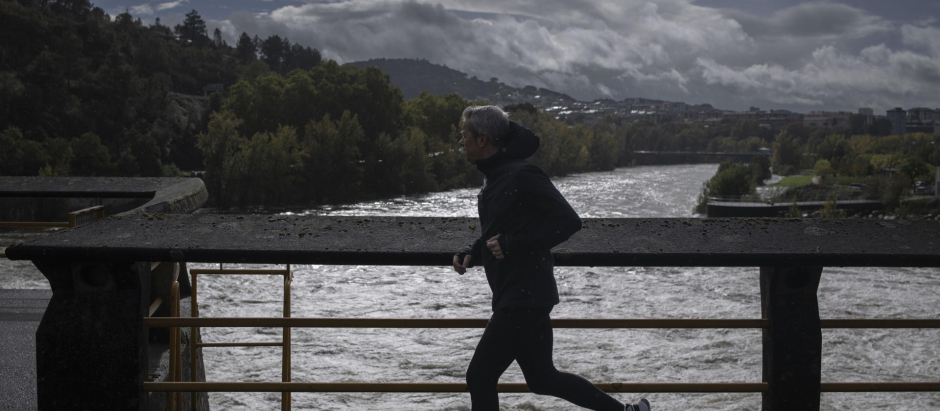 Un hombre corre ante el río Miño a su paso por el embalse de Velle en Ourense