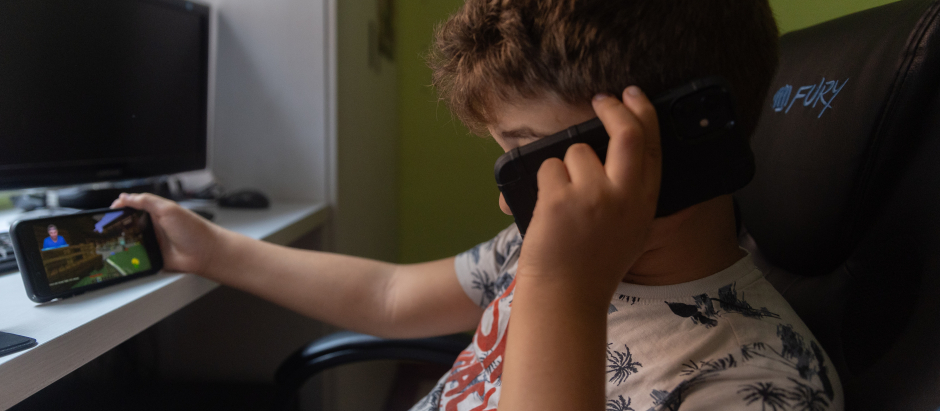 Un niño usa el teléfono móvil y una tablet
