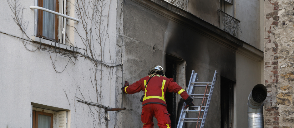 Un bombero inspecciona una ventana quemada después del incendio en París