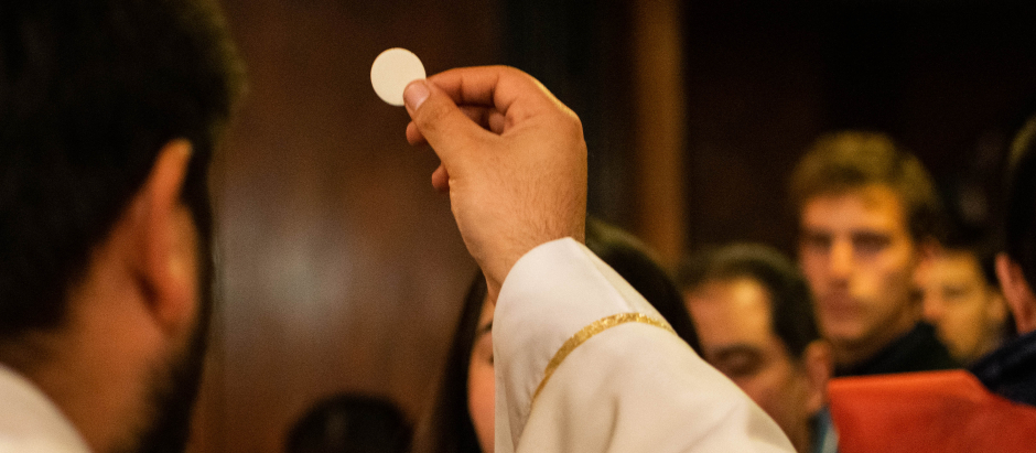 Un sacerdote imparte la comunión a los fieles en Misa