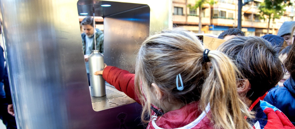Varios niños rellenan sus botellas de agua en la primera fuente de agua refrigerada instalada por el Ayuntamiento de Valencia