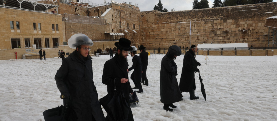 Varias personas caminan sobre la nieve en Jerusalén cubierta de nieve en enero de 2022