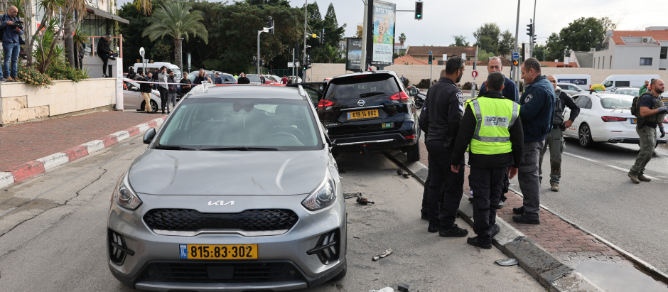 Personal de emergencia y seguridad israelí se encuentra junto a un automóvil dañado en la ciudad israelí de Raanana