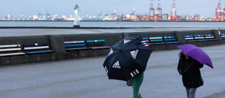 La gente camina por el paseo marítimo de New Brighton mientras la tormenta Isha golpea la costa oeste de Gran Bretaña