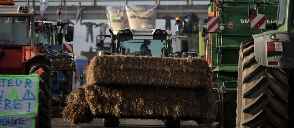 Un agricultor conduce un tractor cargado con bolas de heno durante un bloqueo de la autopista A64, en protesta contra los impuestos y la disminución de ingreso