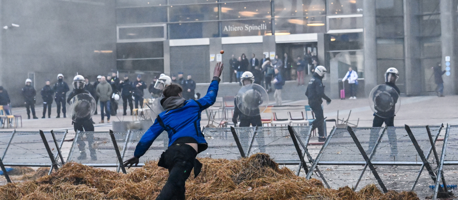 Un manifestante lanza un huevo a agentes de policía belgas cerca de la entrada del edificio del Parlamento Europeo durante la acción de protesta de los agricultores en el distrito europeo de Bruselas