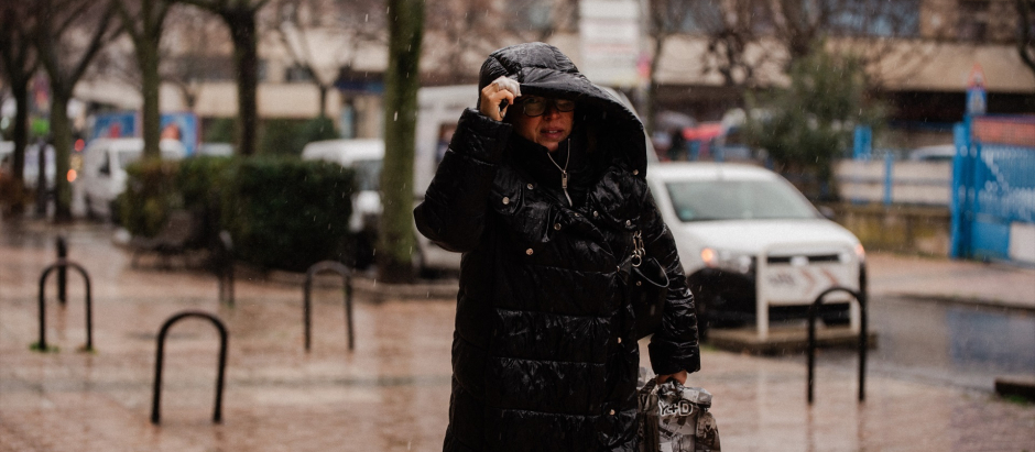 Una persona se protege de la lluvia en Madrid