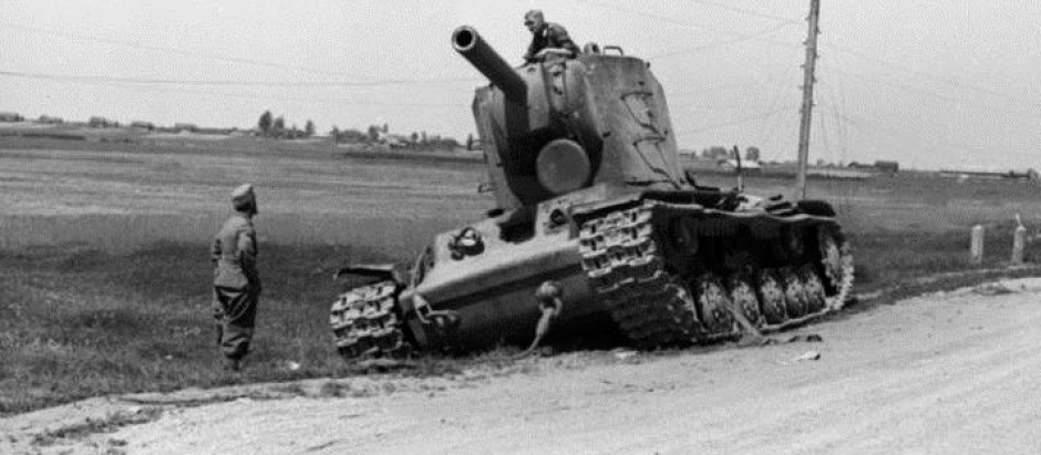 Un tanque soviético KV-2 abandonado al borde de la carretera inspeccionado por curiosos soldados alemanes