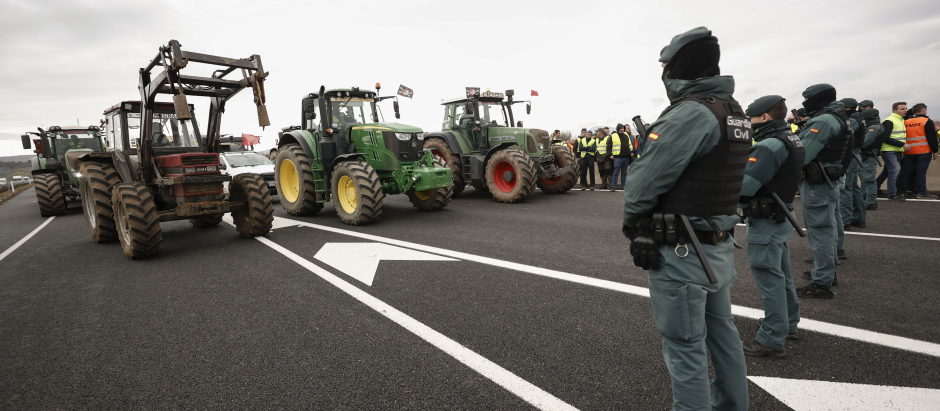 Unos agricultores en la A-12 este jueves frente a agentes de la Guardia Civil que les impiden el paso a Pamplona