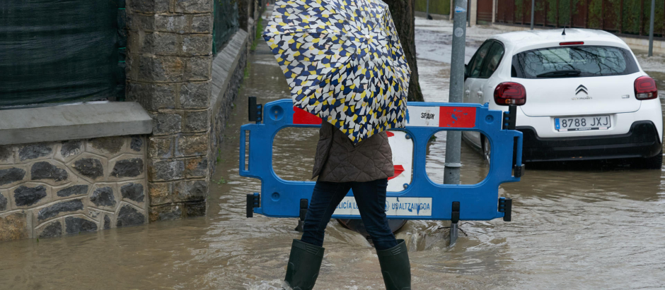 Una mujer pasa por una calle inundada en el barrio del Batán de Vitoria
