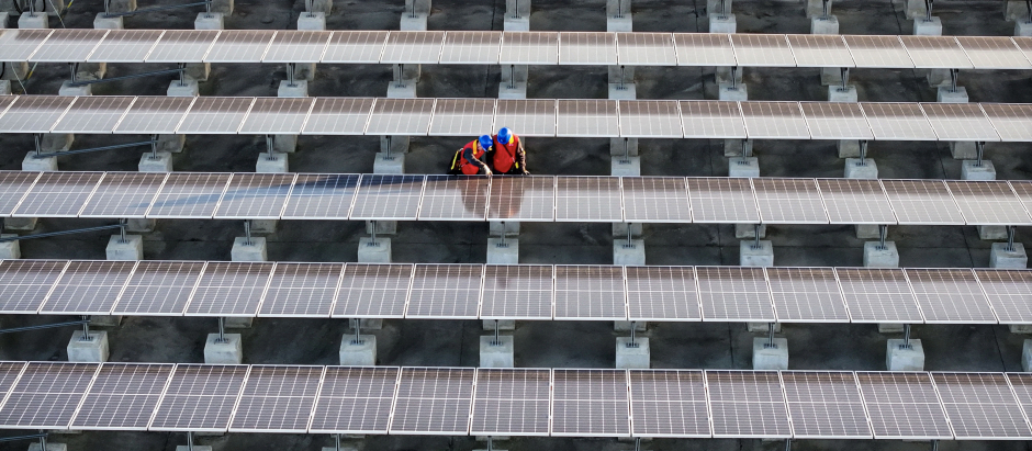 Trabajadores inspeccionan paneles solares en la azotea de una planta de Fuzhou, al sur de China