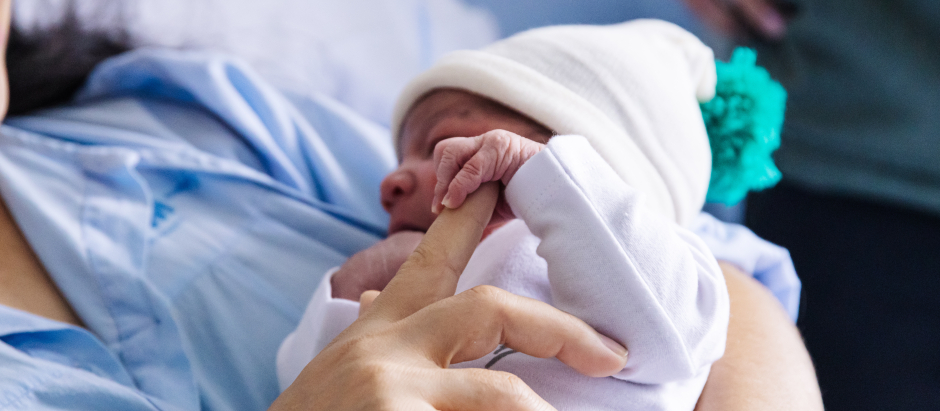 Un bebé recién nacido agarra la mano de su madre
