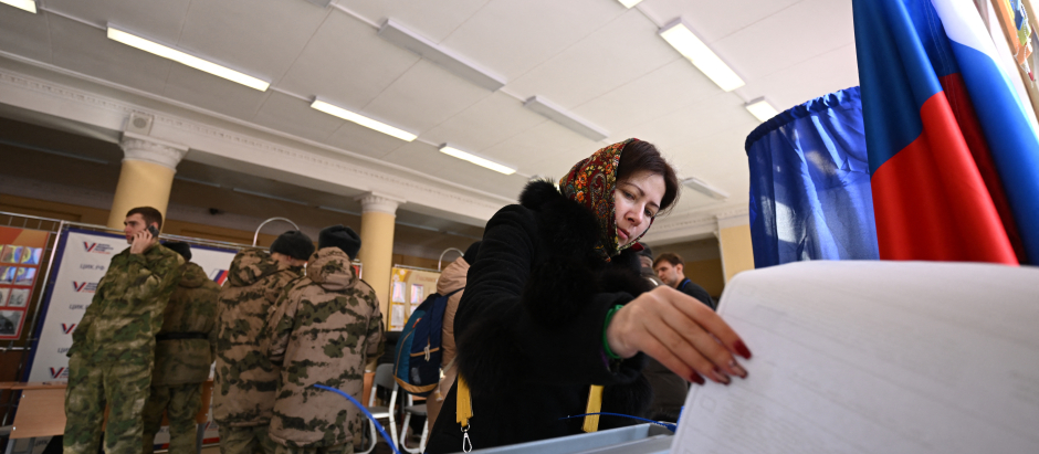 Una mujer vota en un colegio electoral en Rusia bajo una fuerte presencia militar