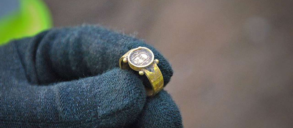 Uno de los arqueólogos sostiene el anillo de oro con el rostro de Cristo que pudo pertenecer a una mujer