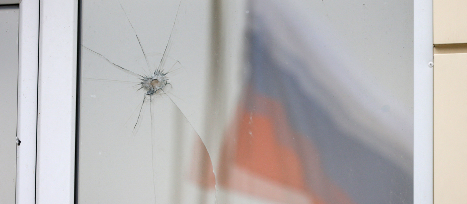 Una bandera rusa reflejada en una ventana dañada tras nuevos ataques aéreos