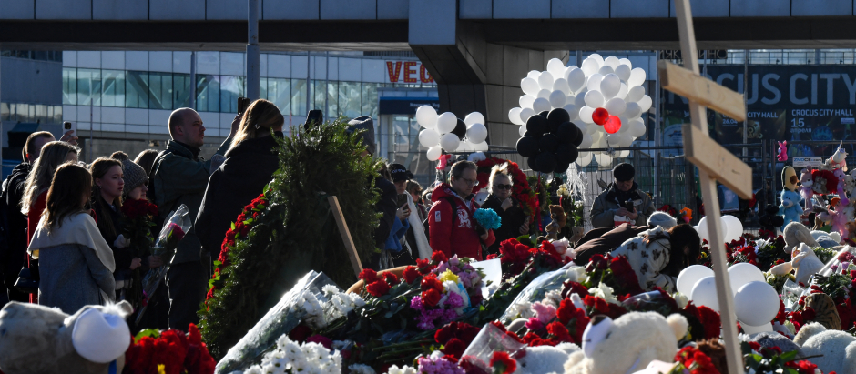 La gente lleva flores a un monumento improvisado frente a la incendiada sala de conciertos Crocus City Hall