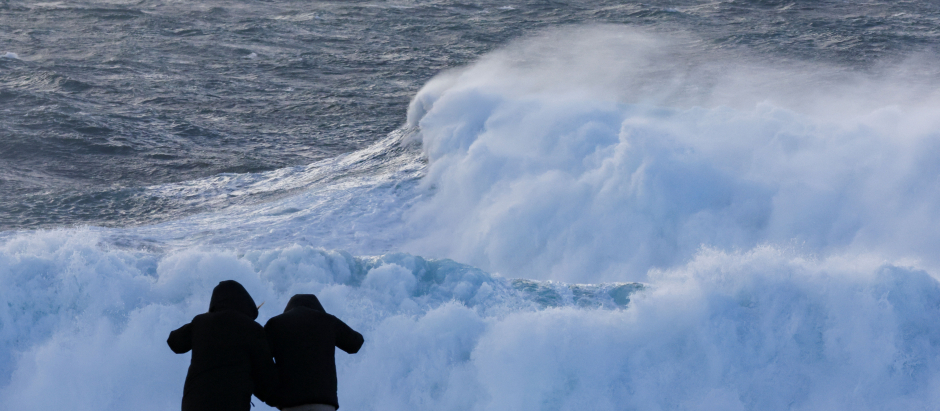 Dos turistas observan el oleaje en la costa de Muxía, este pasado miércoles en La  Coruña. Los días festivos de Semana Santa han estado dominados por la borrasca Nelson que va a dejar fuertes rachas de viento, nieve, mal estado de la mar y sobre todo lluvias en casi toda la península