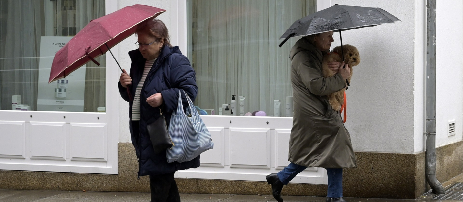 Dos personas se refugian del viento con paraguas