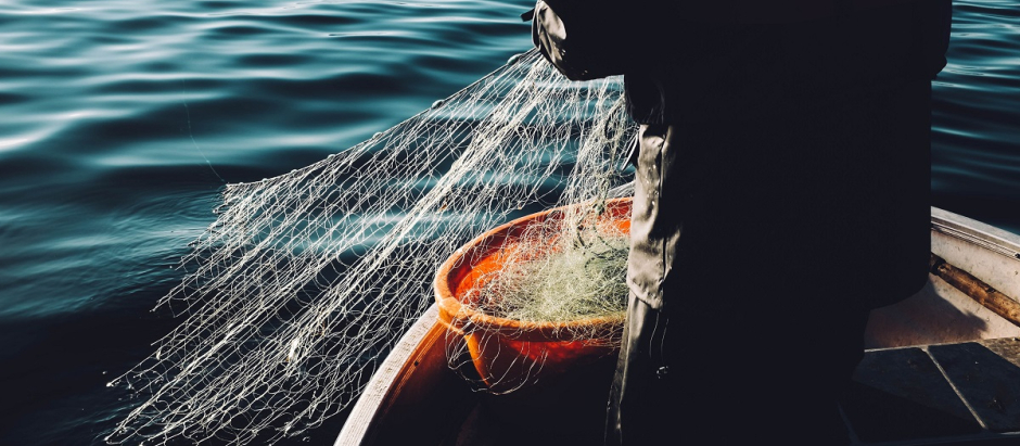 Un pescador recoge una red en el mar